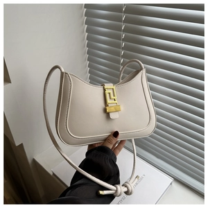 Detail of off-white shoulder bag with golden geometric clasp and knotted leather strap