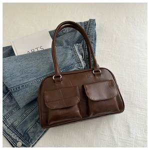 Nahaufnahme der braunen Ledertasche mit quadratischem Patchwork und silbernen Metallringen