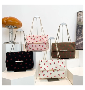 Detail view of corduroy crossbody bags with strawberry prints in four trendy colors