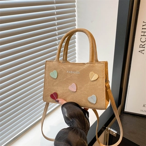 Khaki canvas tote bag with fashion text and colorful hearts decor shown in hand