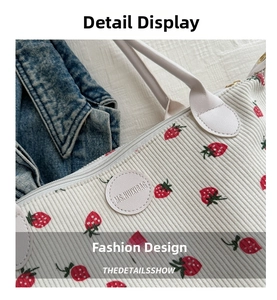 Close-up of strawberry print on beige corduroy tote bag with leather logo patch