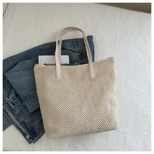 Dettaglio della borsa tote intrecciata beige con trama a rete e manici in pelle rinforzata