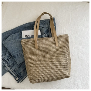 Dettaglio della trama della borsa tote in paglia intrecciata con manici in ecopelle