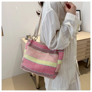 Detail of colorful woven tote bag with pink and yellow stripes and white leather strap
