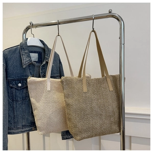Vista dettagliata di borse tote intrecciate in beige e kaki con manici in pelle su gruccia