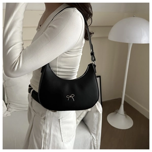 Detailed view of black crescent hobo bag with silver metallic bow on a female model