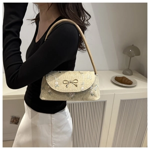 Détail du sac sous le bras tressé beige avec broderie florale rose et boucle de noeud dorée