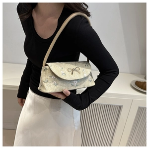 Détail d'un sac en paille beige avec broderie florale et nœud en métal