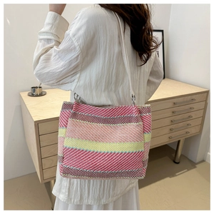 Detail of colorful knitted shoulder bag with rainbow stripes and white handle worn by a model