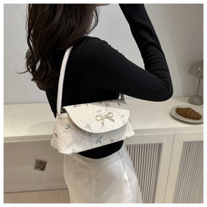 Détail du sac bandoulière tissé avec broderie florale et fermoir nœud doré