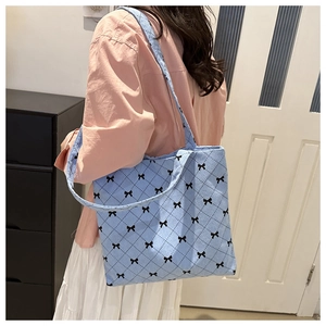 Detail of light blue corduroy tote bag featuring black bow and diamond pattern