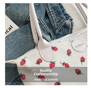 Close-up of strawberry print on white corduroy tote bag with round leather logo label