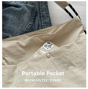 Détail du sac bandoulière en toile avec poche pour smartphone et sangles tissées