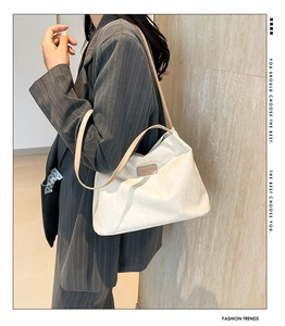 Detail of white textured fabric shoulder bag with leather strap on a striped blazer