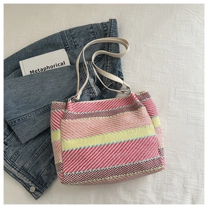 Macro detail of rainbow striped woven tote bag with slim faux leather shoulder straps