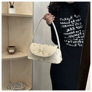 Gros plan du sac en paille tressée avec broderie florale et fermoir papillon doré