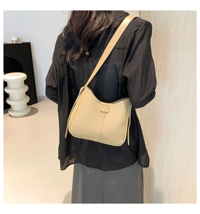Detailed view of apricot faux leather shoulder bag with vertical stitching and buckle