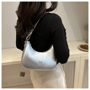 Detail of silver matte crescent bag with delicate metal bow buckle and sleek shoulder strap