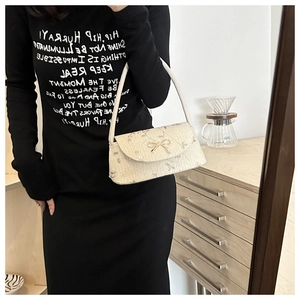 Détail du sac en paille tressée avec broderies florales et boucle nœud doré