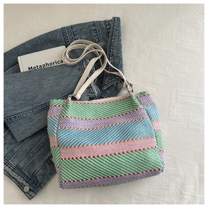 Close-up of colorful striped woven tote bag with white leather handles and denim jacket