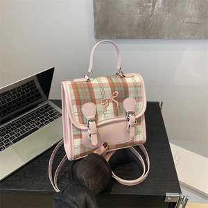 Pink plaid backpack for women with bow embroidery and metal buckles on a wooden desk