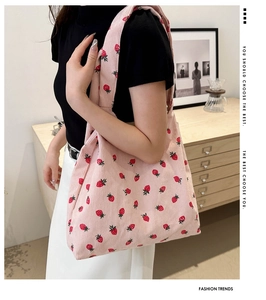 Close-up of pink corduroy tote bag featuring red strawberry prints and ribbed texture