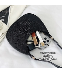 Detail view of black crocodile pattern hobo bag interior holding phone and daily items