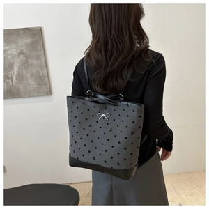 Rear view of a model wearing the polka dot tote bag with leather bottom and silver bow