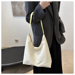 Détail d'un sac hobo crème texturé avec bandoulière jaune vif porté à l'épaule