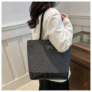 Detail of dark grey tote bag featuring black heart patterns and silver bow buckle