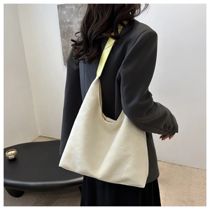 Detail of cream knit tote bag with yellow strap showing textured fabric on shoulder