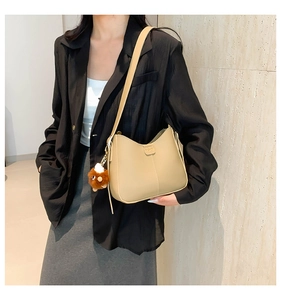 Detail view of beige bucket bag with plush charm and vertical stitching on the side