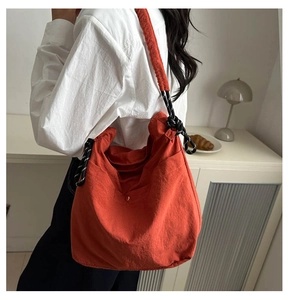 Détail du sac à bandoulière en toile orange avec sangle nouée et texture plissée