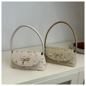 Détail de broderie florale et boucle nœud dorée sur des sacs à main tissés à la main