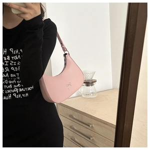 Detailed view of pink crescent bag with silver bow ornament and smooth matte finish