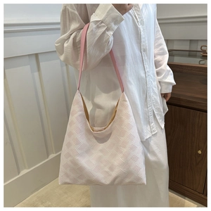 Détail de la texture tissée à bulles et de la bandoulière en cuir rose sur un grand sac hobo