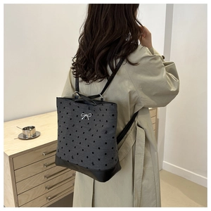 Lifestyle shot of grey polka dot backpack with black leather straps on a female model