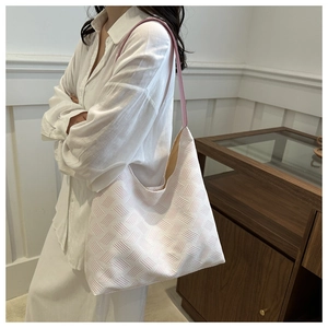 Side view of a large pink and white woven tote bag worn on shoulder for daily commute