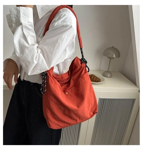 Détail du sac seau orange avec bandoulière texturée noire et blanche et boucle métallique