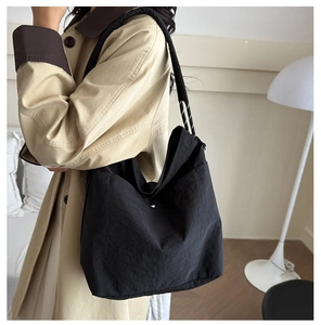 Détail du grand sac fourre-tout noir en nylon avec une texture plissée et bouton pression