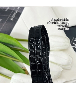 Detail of black faux crocodile leather strap with glossy texture for shoulder bag