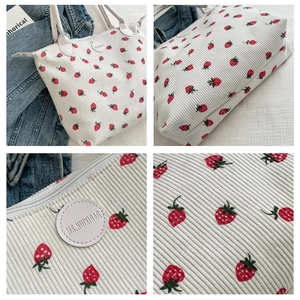 Detail of strawberry print on corduroy tote bag showing texture and circular logo