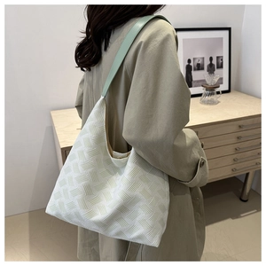 Close-up of stylish bubble texture shoulder bag with green strap in a minimalist room