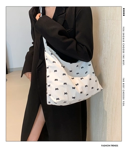 Detail shot of the large white hobo bag featuring a black bow pattern and soft canvas texture