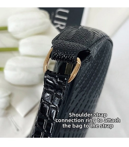 Close-up of golden metal ring hardware and crocodile pattern texture on shoulder bag