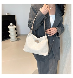 Close-up of beige woven tote bag with leather tag styled with a grey business suit