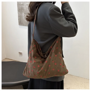 Detail of a brown corduroy tote bag featuring a cute red strawberry print pattern