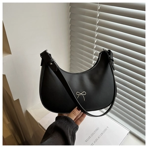 Detail of black matte crescent hobo bag with a delicate silver bow charm accessory