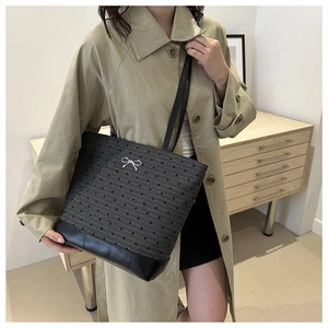Close-up of heart pattern tote bag with silver bow detail on minimalist khaki coat