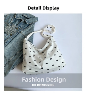 Close-up of white canvas crossbody bag with black bow print and zipper detail